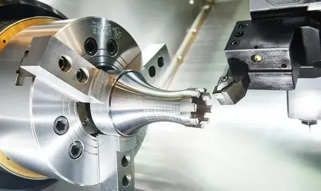A CNC turning machine being used to create precise, complex parts using a lathe tool. The finished product, a small, intricately designed gear, sits alongside the machine.